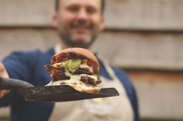 The Game Chef holding a burger